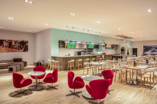 a restaurant with red chairs and tables and a bar at Fiesta Inn Los Mochis in Los Mochis