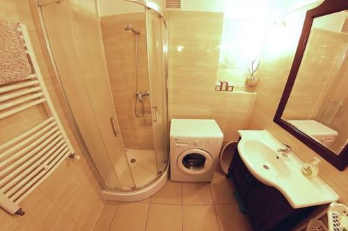 a bathroom with a shower sink and a washing machine at Apartament Teresa in Łeba