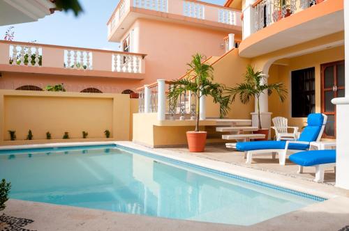 a swimming pool in front of a building with chairs and a hotel at Righetto Vacation Rentals in Puerto Morelos