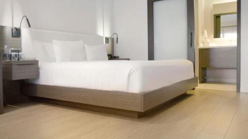 a bedroom with a large white bed and a bathroom at The Nest Hotel Palo Alto in Palo Alto