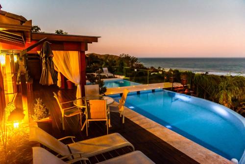 a house with a swimming pool and the ocean at Morada Prainha in Garopaba