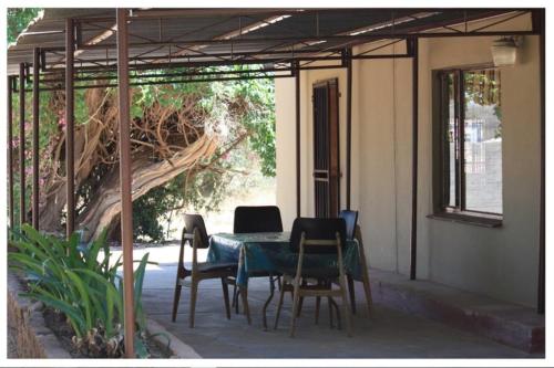 eine Terrasse mit einem Tisch, Stühlen und einem Baum in der Unterkunft Abuelita Guesthouse - Room 2 in Lephalale