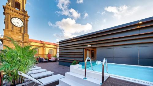 ガルダーにあるHotel Emblemático Agáldarの時計塔とスイミングプールのある建物