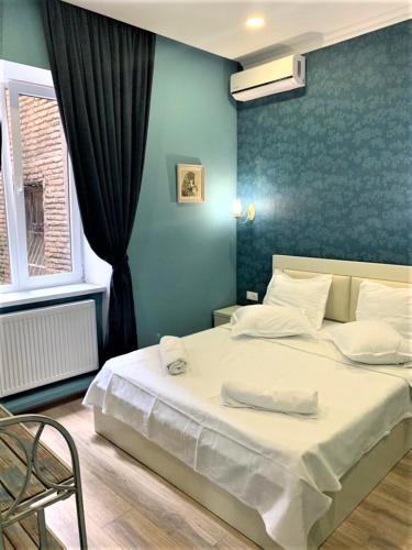 a bedroom with a white bed with a blue wall at Griboedov 13 in Tbilisi City