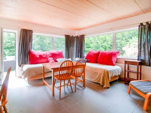 Schlafzimmer mit einem Bett mit roten Kissen und einem Tisch in der Unterkunft Halfway between the town of Spa and Nature Park High Venn in Jalhay