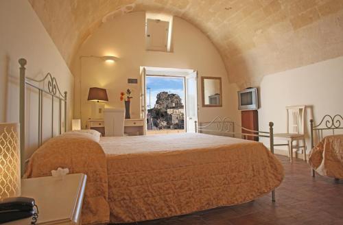 Un dormitorio con una cama grande y una ventana en Caveoso Hotel en Matera