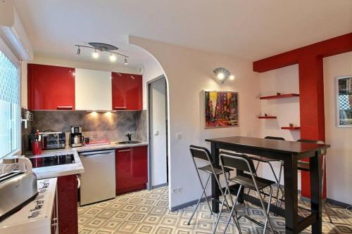 een keuken met rode kasten en een tafel en stoelen bij Charmant T1 à proximité centre ville in Avignon