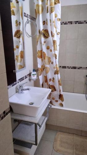 a bathroom with a sink and a tub and a shower curtain at Classic-style apartment in Loutra Edipsou