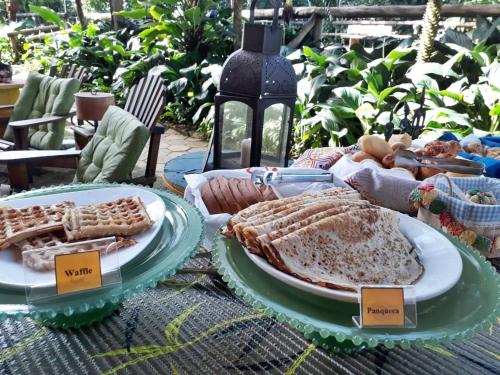 a table with plates of food on top of it at Pousada Portal do Cacau-Petfriendly in Camburi