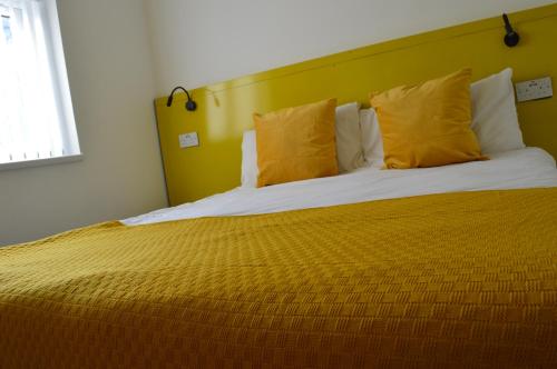 um quarto com uma cama grande e almofadas amarelas em Bell Gate House em Leicester