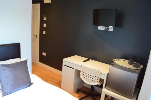 a bedroom with a desk and a bed and a tv at Bell Gate House in Leicester