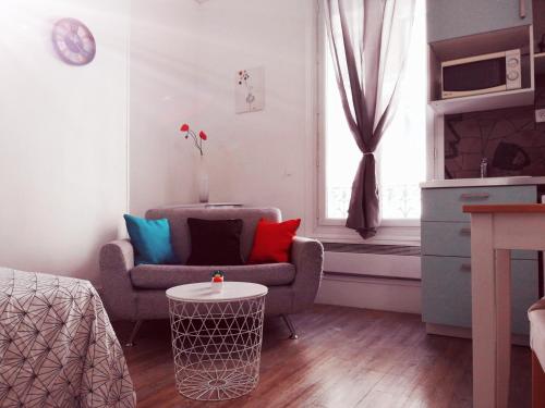 a living room with a chair and a table at Studio situé dans un quartier calme et résidentiel à Montrouge à seulement 2 minutes du métro in Montrouge