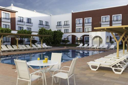 un hôtel avec une table, des chaises et une piscine dans l'établissement Fiesta Inn Queretaro, à Querétaro