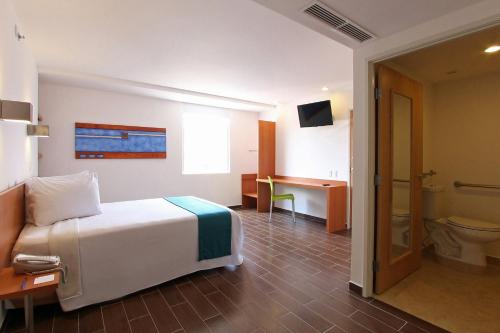 a bedroom with a bed and a bathroom with a toilet at One Villahermosa Centro in Villahermosa