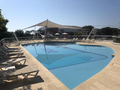 uma grande piscina azul com cadeiras e uma tenda em One Acapulco Diamante em Acapulco