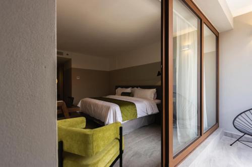 a bedroom with a bed and a green chair at Gamma Orizaba Grand Hotel de France in Orizaba