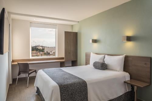 a hotel room with a bed and a window at One Puebla Serdan in Puebla
