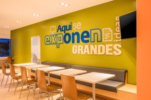 a restaurant with tables and chairs and a green wall at One Puebla Serdan in Puebla
