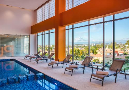 a hotel pool with chairs and a view of the mountains at Fiesta Inn Express Puebla Explanada in Puebla