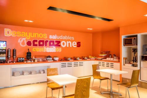 a restaurant with orange walls and tables and chairs at One Puebla Serdan in Puebla
