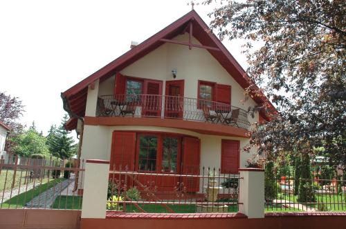 a house with red doors and a balcony at Marina Panzio in Siófok