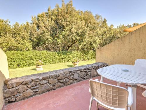 un patio con tavolo, sedie e parete in pietra di Belvilla by OYO Le Mimose nr 11 a Punta Ala