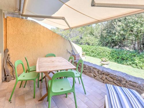 un patio con tavolo in legno e sedie verdi di Belvilla by OYO Le Mimose nr 12 a Punta Ala