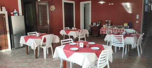 ein Restaurant mit weißen Tischen und Stühlen und roten Wänden in der Unterkunft Villa Pollina in Buseto Palizzolo