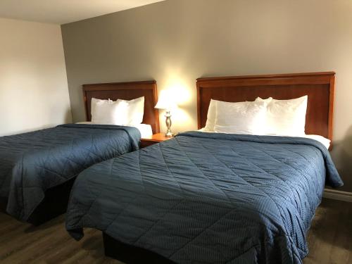 a hotel room with two beds and a lamp at Aquarius Motel in Perth