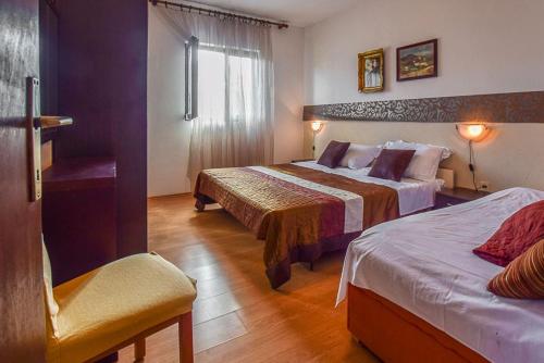 Habitación de hotel con 2 camas y ventana en Apartments Derado, en Supetar
