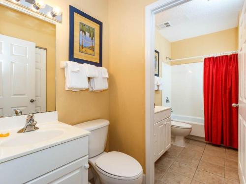 a bathroom with a white toilet and a red shower curtain at Windemere Condominiums in Perdido Key