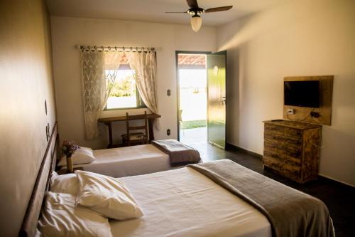 a hotel room with two beds and a television at Pousada Flor da Serra in Cruzeiro