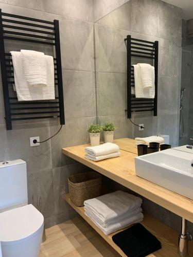a bathroom with a sink and a toilet and towels at Pine Apartment - a 3m da ciclovia Guincho in Cascais