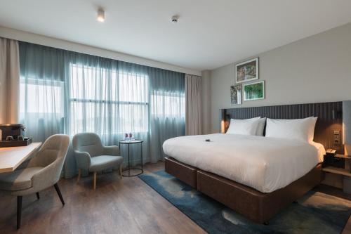 a hotel room with a bed and a desk and chairs at Crowne Plaza Utrecht - Central Station, an IHG Hotel in Utrecht
