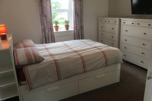 a bedroom with a bed with a dresser and a window at Forest of Dean Country Cottage in Mitcheldean