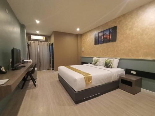 Dormitorio con cama, escritorio y TV en The S Design Hotel, en Buriram