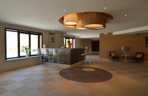 a lobby with a bar with stools at Turin Airport Hotel & Residence in San Francesco al Campo