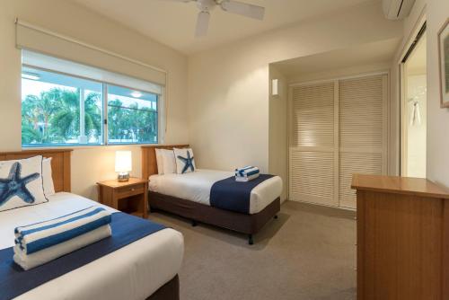 a hotel room with two beds and a window at Mowbray By The Sea in Port Douglas