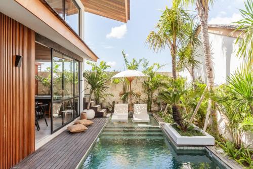 an infinity pool in a house with palm trees at Beyond Bespoke Villas in Seminyak