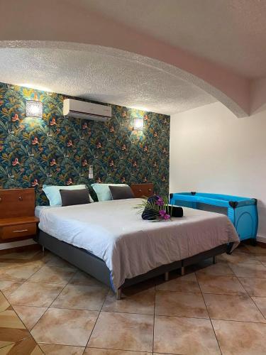 1 dormitorio con 1 cama grande y una pared con flores en Villa Bri, en Rivière