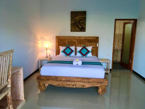 a bedroom with a large bed with a wooden headboard at Agung Inn Amed in Amed