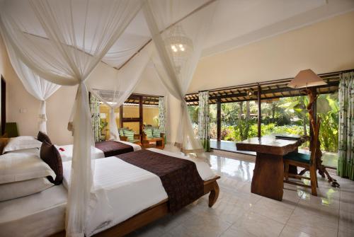 a bedroom with a canopy bed with a desk and a desk at Green Field Hotel and Restaurant in Ubud