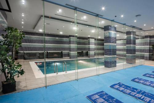 a swimming pool in a building with glass walls at Naviti Warwick Al Khobar in Al Khobar
