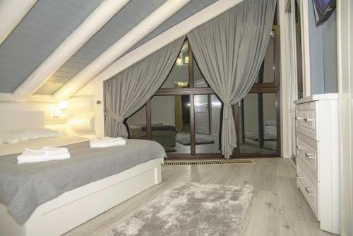 a bedroom with a bed and a large window at Adele in Mizhhirʼʼya