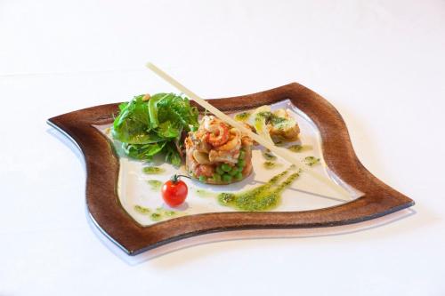 a plate of food on a wooden plate with chopsticks at Hotel le Chalet in Gresse-en-Vercors