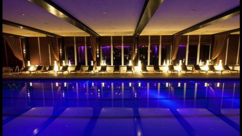 a pool with chairs and lights in a building at Poiana Brasov Alpin Resort Apartment in Poiana Brasov