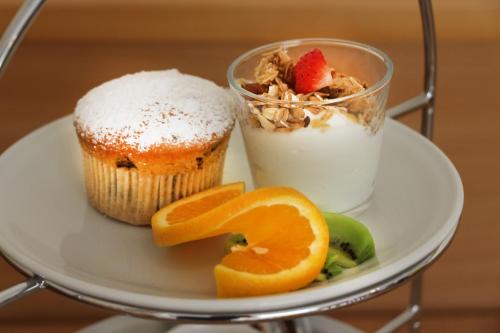 a plate with a cupcake and a drink and fruit at Gästehaus Zehmerhof bei Erding in Walpertskirchen