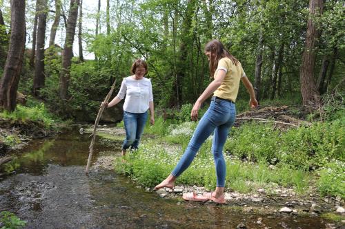 two women walking across a stream with a stick at Gästehaus Zehmerhof bei Erding in Walpertskirchen