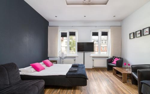 a bedroom with a bed and a couch and a tv at Rainbow Apartments 1 in Krakow