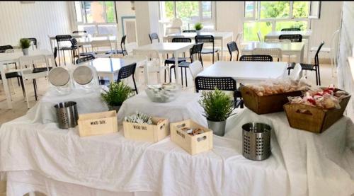 ein weißer Tisch mit Kisten, Tischen und Stühlen in der Unterkunft Albergue Internacional de Llanes in Llanes